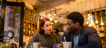 Ett par som sitter på ett cafe och dricker kaffe